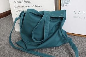 Detailed view of dark green canvas tote bag with reinforced stitching and adjustable strap