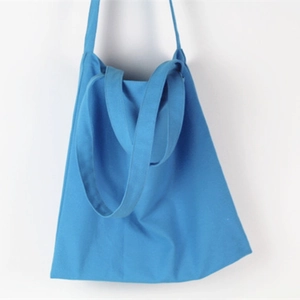 Detail of light blue canvas tote bag featuring dual handles and a long shoulder strap