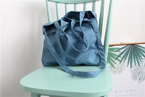 Detailed view of dark blue canvas tote bag stitching on a mint green wooden chair