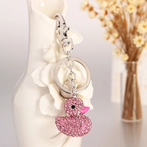 Pink rhinestone duck keychain with silver lobster clasp on decorative white vase