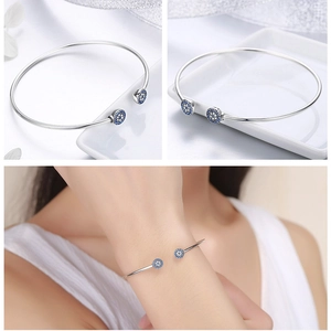 Detail view of silver open bangle featuring sparkling blue and white zircon eye patterns