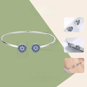Detail of 925 sterling silver open bangle with blue evil eye zircon charms