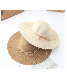 Detail of straw sun hats in beige and light brown with colorful bead string accents