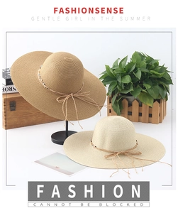 Detail of wide brim straw sun hats in beige and brown colors with decorative beaded strings