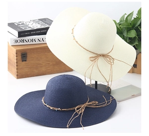 Detailed straw sun hat with decorative bead string and bow on a white display stand
