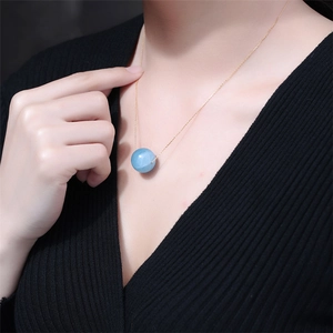 Close-up of a blue crystal bead pendant necklace worn on a black knit sweater