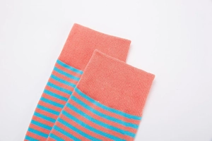 Close-up of ribbed cuffs on coral and blue striped knitted crew socks for men