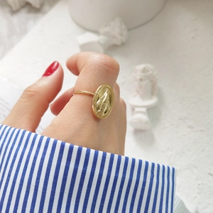 Close-up of a gold-plated oval religious coin ring featuring a vintage medallion design