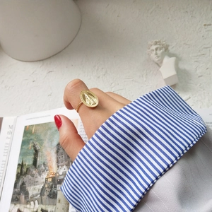 Macro view of a gold-plated oval religious medal ring worn by a model on index finger