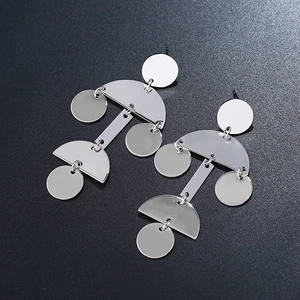Detailed view of silver geometric pendant earrings with round metal discs on black background