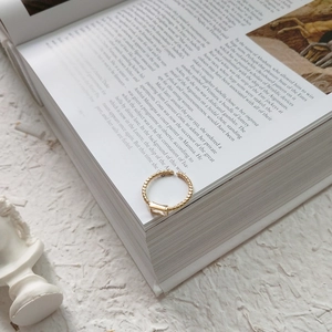 Close-up of golden S925 silver beaded ring with rectangular crystal on vintage book