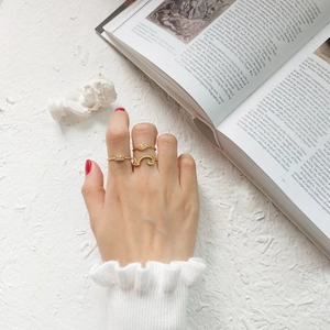 Detailed view of three-piece gold ring set with wave, eye motifs and zircon accents