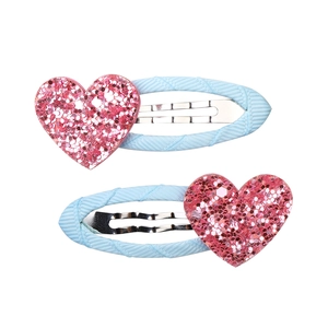 Dettaglio di due fermagli per capelli a cuore rosa glitterato con nastro azzurro