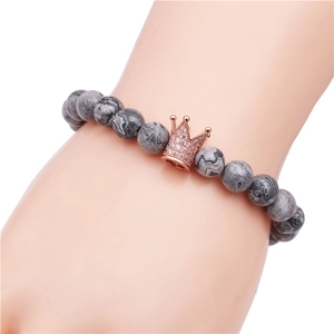 Bracelet en perles de marbre gris 8mm avec couronne en or rose porté au poignet d'un homme