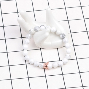 Détail d'un bracelet en perles de turquoise blanche 8mm avec un charm couronne or rose