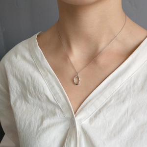 Detail shot of minimalist 925 sterling silver irregular oval pendant on model's neck