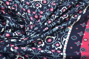 Close-up of bohemian scarf fabric showing pink floral patterns on navy blue texture