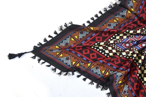 Detail of bohemian scarf featuring colorful geometric patterns and black fringe trim