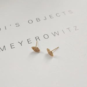 Detailed close-up of gold eye-shaped 925 sterling silver stud earrings on a white book