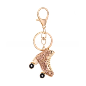 Detail of a gold roller skate keychain with pink rhinestones, ring, and lobster clasp