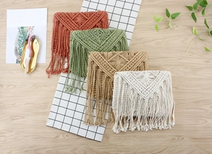 Flachbild von bunten böhmischen Makramee-Strohtaschen mit langen Quasten auf Holzgrund