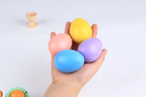 Main tenant quatre œufs de Pâques colorés en bois pour peinture DIY et artisanat enfant