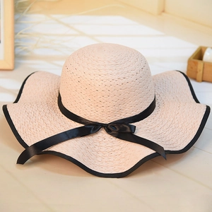 Detailed straw weave texture on a cream sun hat with an elegant black ribbon bow