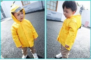 Detailed view of yellow kids raincoat featuring a transparent hood brim and snap buttons