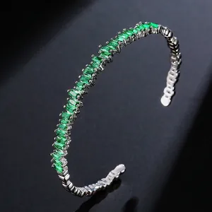Silver cuff bangle featuring emerald green rectangular zircons in a single row setting