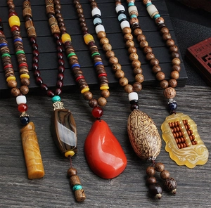 Ethnic wood bead necklaces featuring various jade and agate pendants on rustic wood background