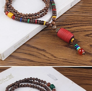 Detailed view of ethnic wooden bead necklace with a large red barrel bead and tassel