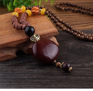 Detailed close-up of ethnic style wooden bead necklace with a large round resin pendant