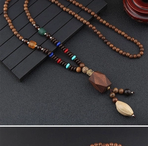 Close-up of ethnic long necklace with wooden beads and a geometric pendant charm