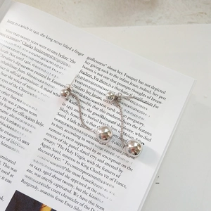 Macro detail of silver tassel earrings with round metal beads on a vintage book