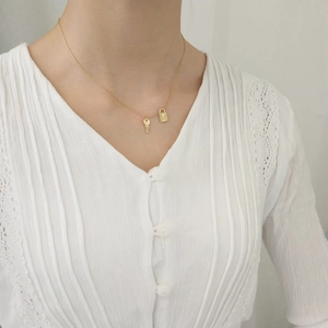 Detail of a 925 silver gold-plated necklace with a delicate lock and key pendant charms
