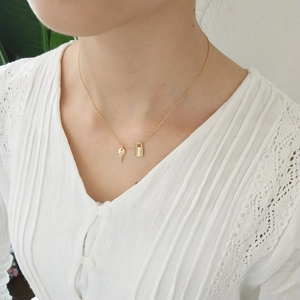 Close-up of a 925 silver golden necklace featuring minimalist lock and key pendants
