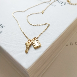 Macro detail of minimalist gold 925 silver necklace with lock and key pendant design