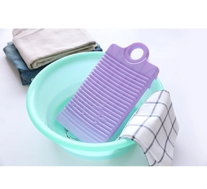 Close-up of a purple plastic washboard in a basin with laundry and household items