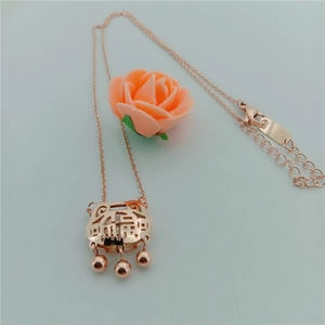 Detail of rose gold pig zodiac lock necklace with traditional Fu character and floral accent