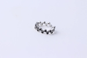 Detail of wavy S925 silver ring with black zircon stones and textured open band