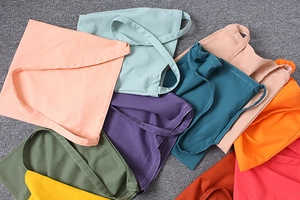Close-up of stacked colorful cotton canvas tote bags showing fabric texture and neat stitching