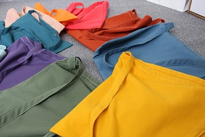 Close-up of colorful canvas tote bags showing reinforced white stitching and fabric texture