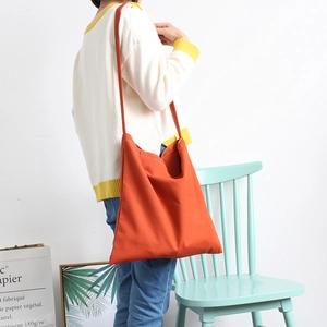 Minimalist bright orange canvas crossbody bag for women shown on model in a casual setting
