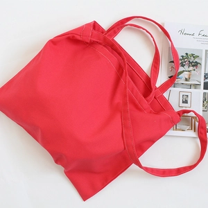Detail shot of bright red canvas tote bag showing white stitching and durable cotton fabric
