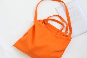 Top view of bright orange canvas tote bag with white stitching and long shoulder strap