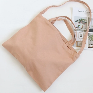 Detail of solid color canvas tote bag showing stitching, dual handles and long shoulder strap
