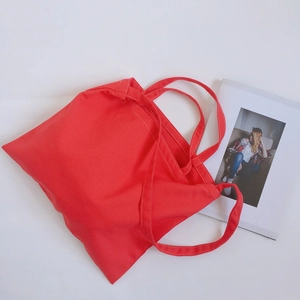Detailed view of red canvas tote bag with precise stitching and natural cotton texture