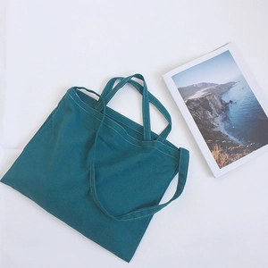 Detail of dark green canvas tote bag featuring white contrast stitching and dual handles