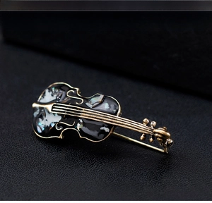 Macro detail of cello brooch with natural shell inlay and vintage gold metal plating