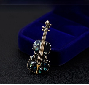 Macro view of vintage violin brooch with abalone shell inlay on navy velvet gift box